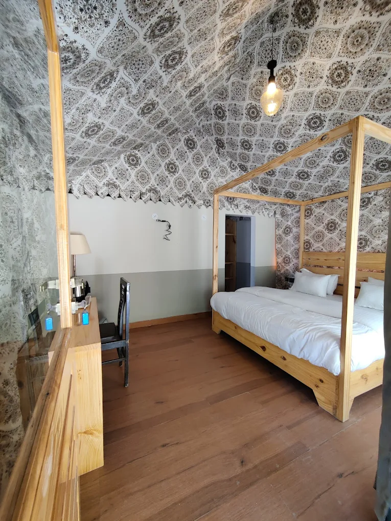 A bright cottage bedroom with a wooden canopy bed and patterned ceiling