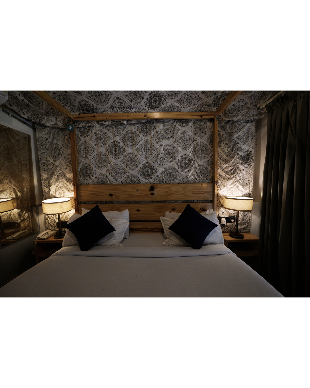 A cottage bed lit by warm bedside lamps