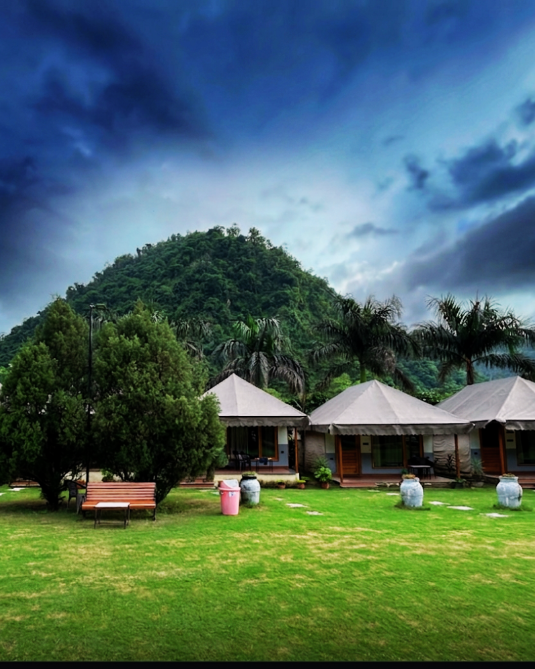Maldevta Farms cottages facing a green lawn beneath the forested hills